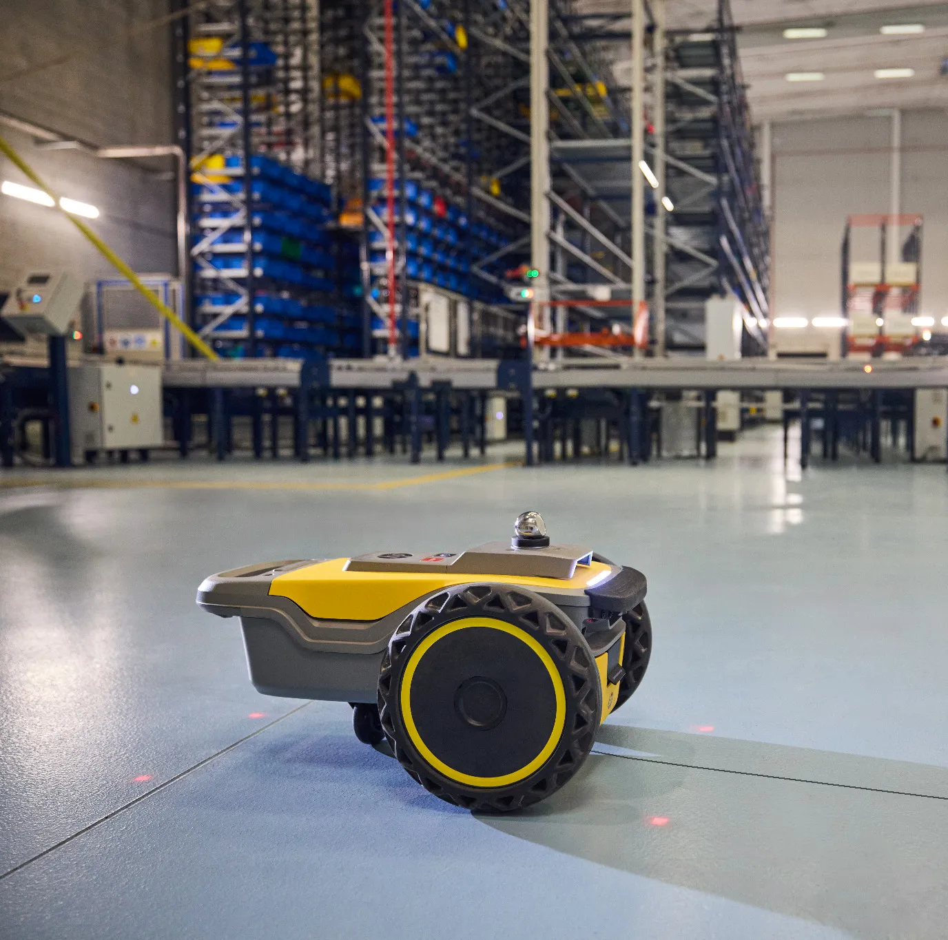 Robot traceur autonome jaune stationné sur une dalle de béton dans un bâtiment industriel